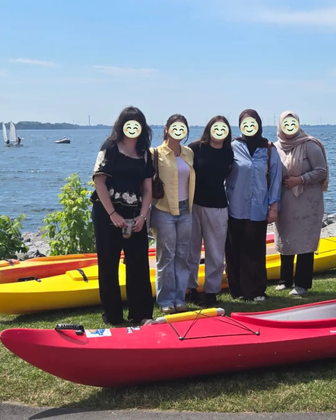 Five GRFS Grade 12 students standing beside red and yellow kayaks on the Kingston waterfront