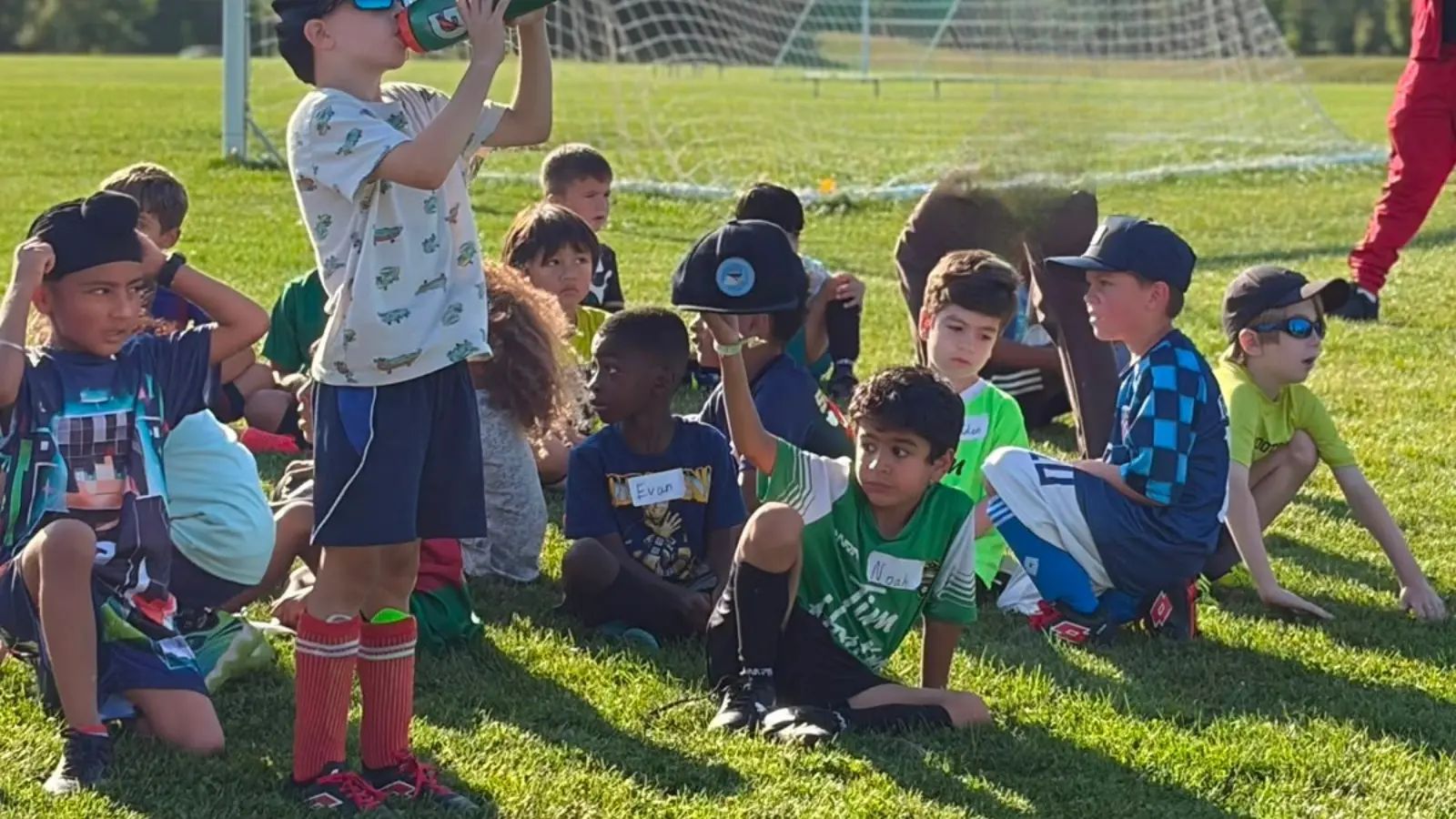Children resting together on the field during a GRFS summer soccer training session.