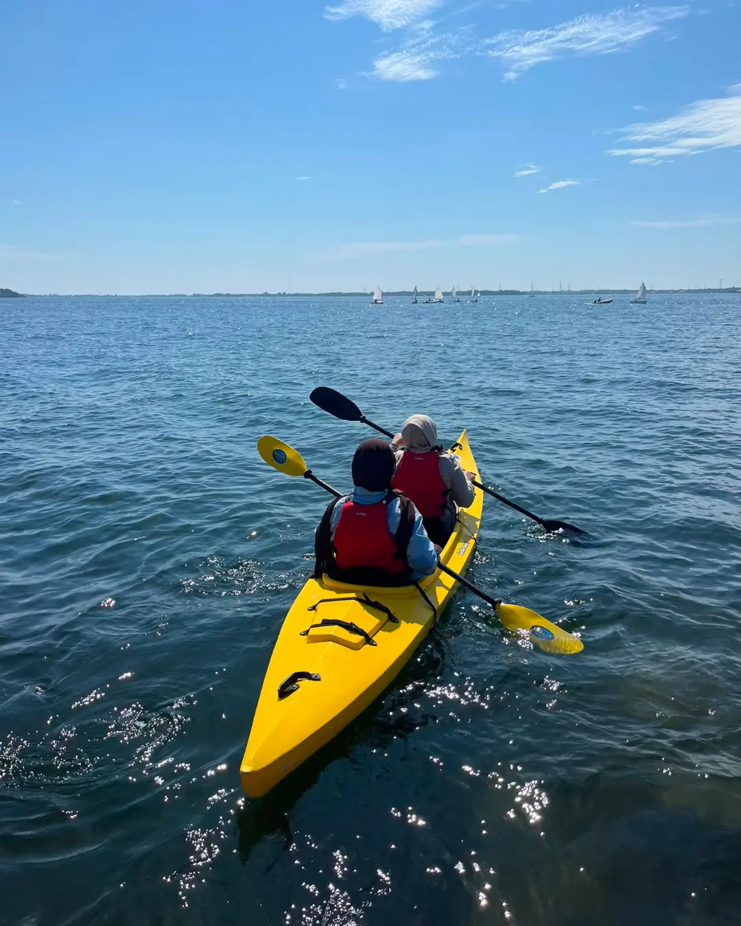 Two GRFS Grade 12 students paddling a yellow tandem kayak on the Kingston waterfront