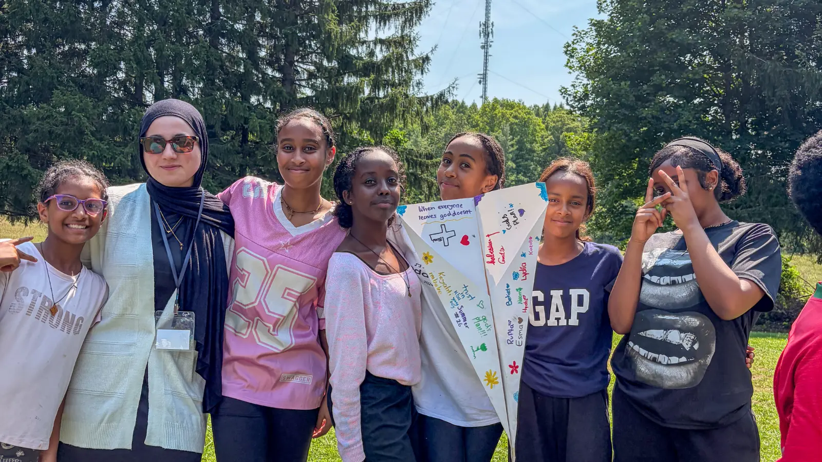 Participants and a mentor displaying a decorated paper airplane during a Kids To Camp 2026 STEM challenge.