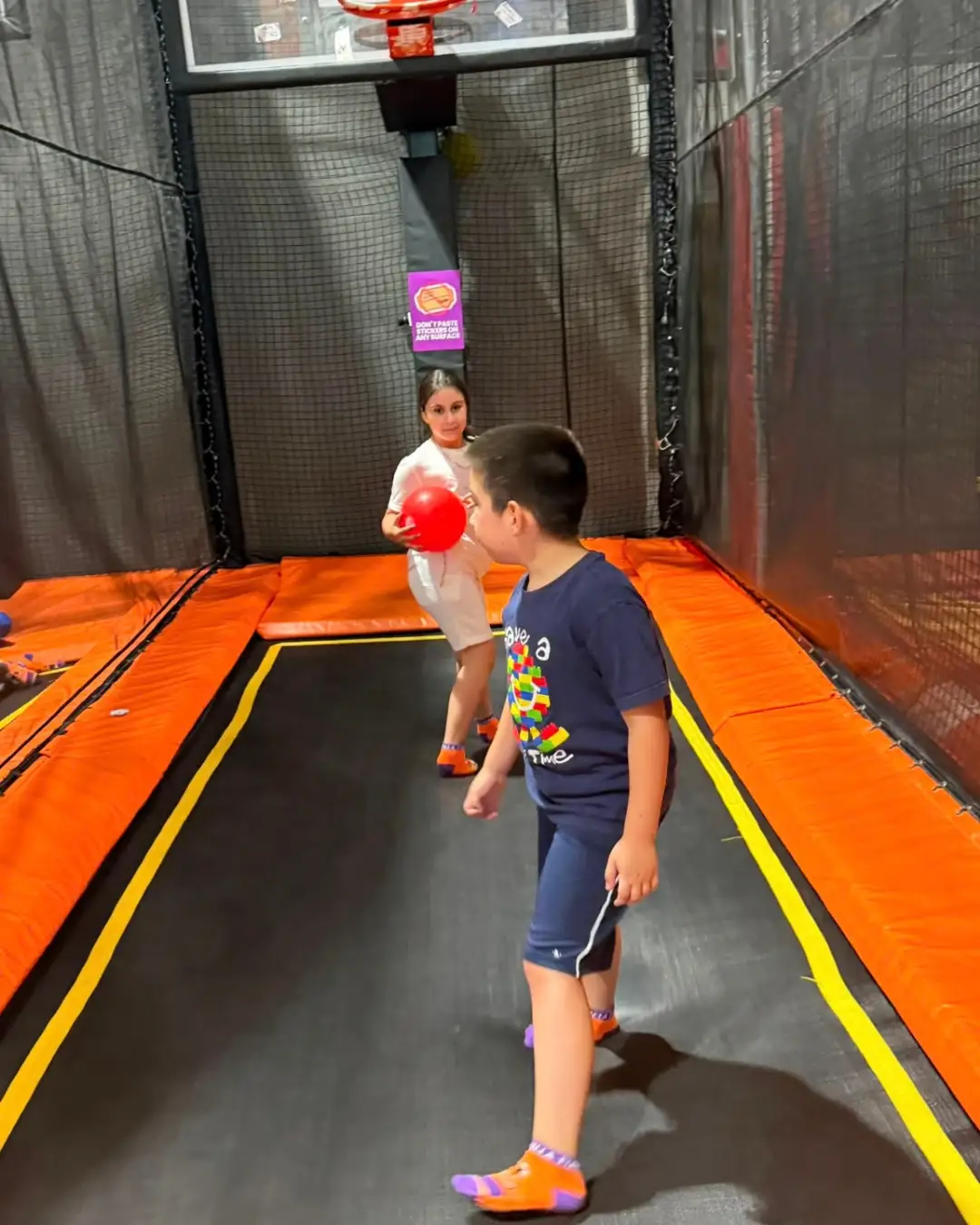 Two children playing with a ball in a trampoline basketball area at GRFS Summer School 2026