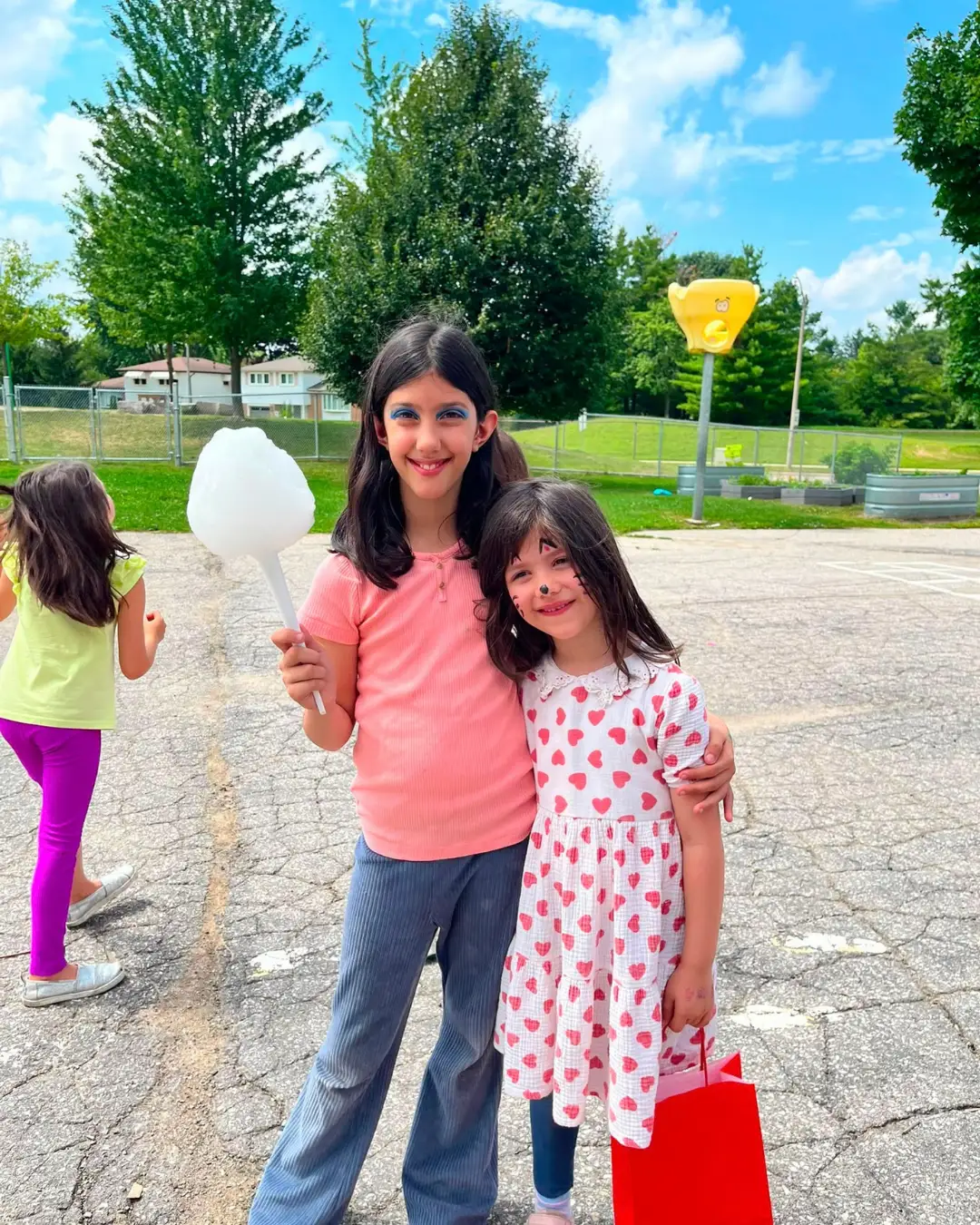 Two children enjoying cotton candy and face painting outdoors at GRFS Summer School 2026