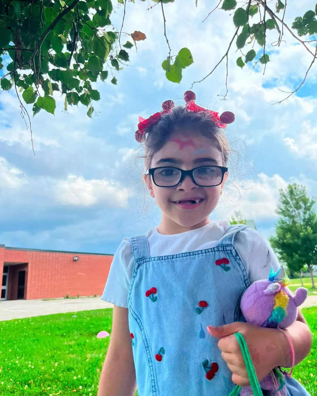 A child with face paint holding a plush toy outdoors at GRFS Summer School 2026