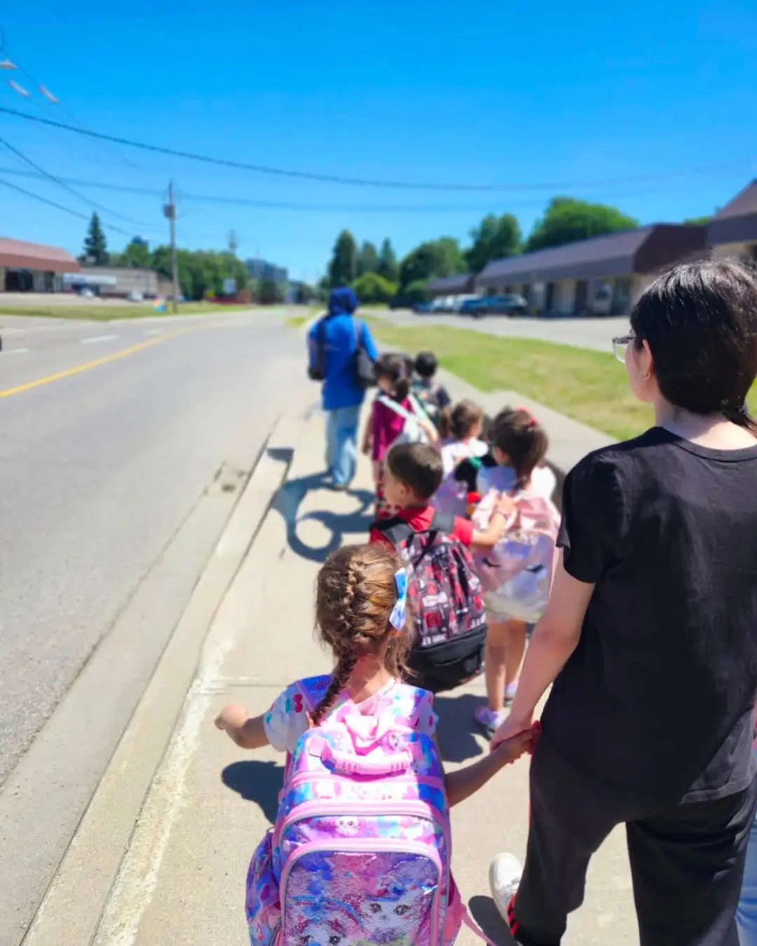 Children and mentors walking together along a sidewalk at GRFS Summer School 2026