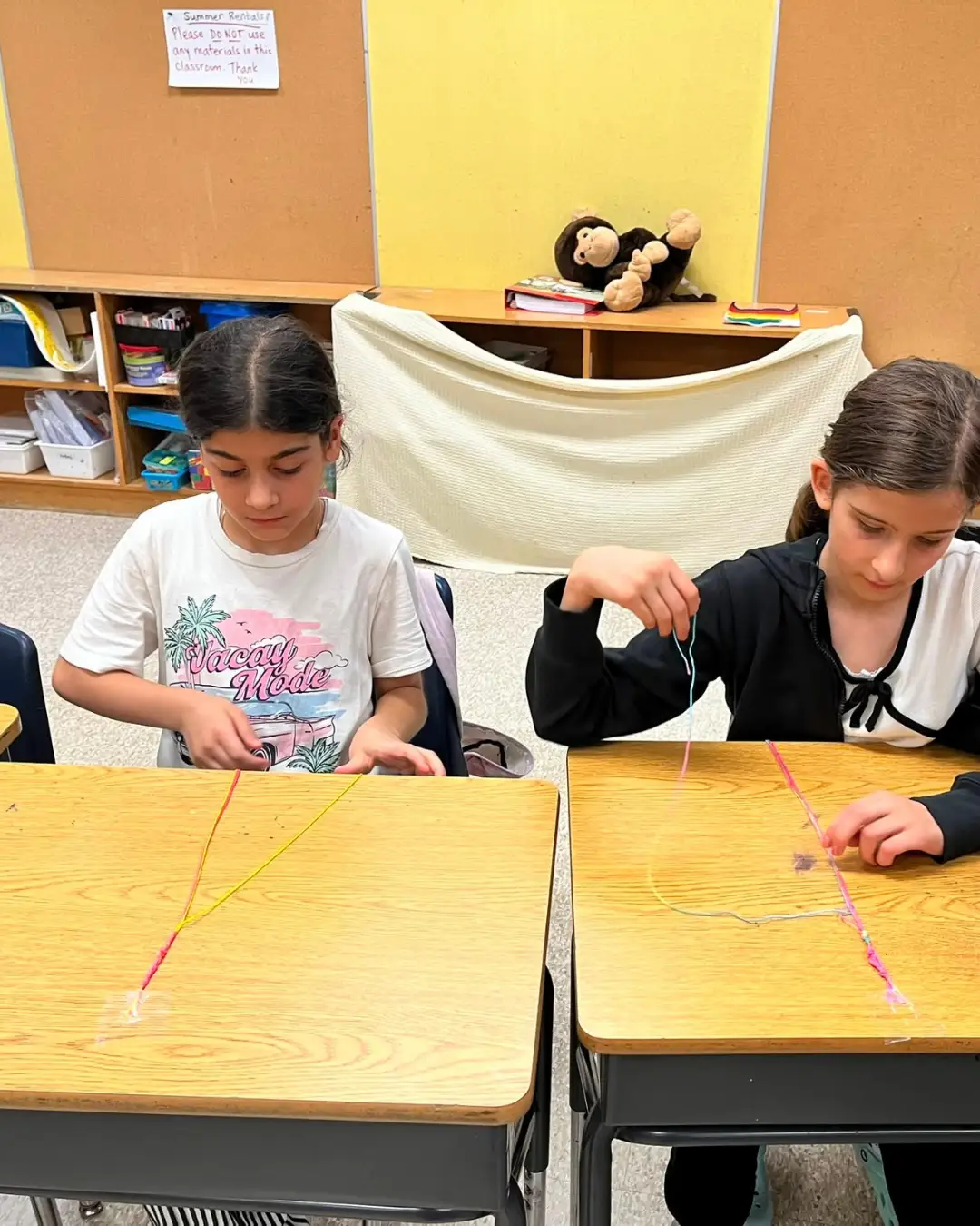 Two children making string bracelets at classroom desks at GRFS Summer School 2026