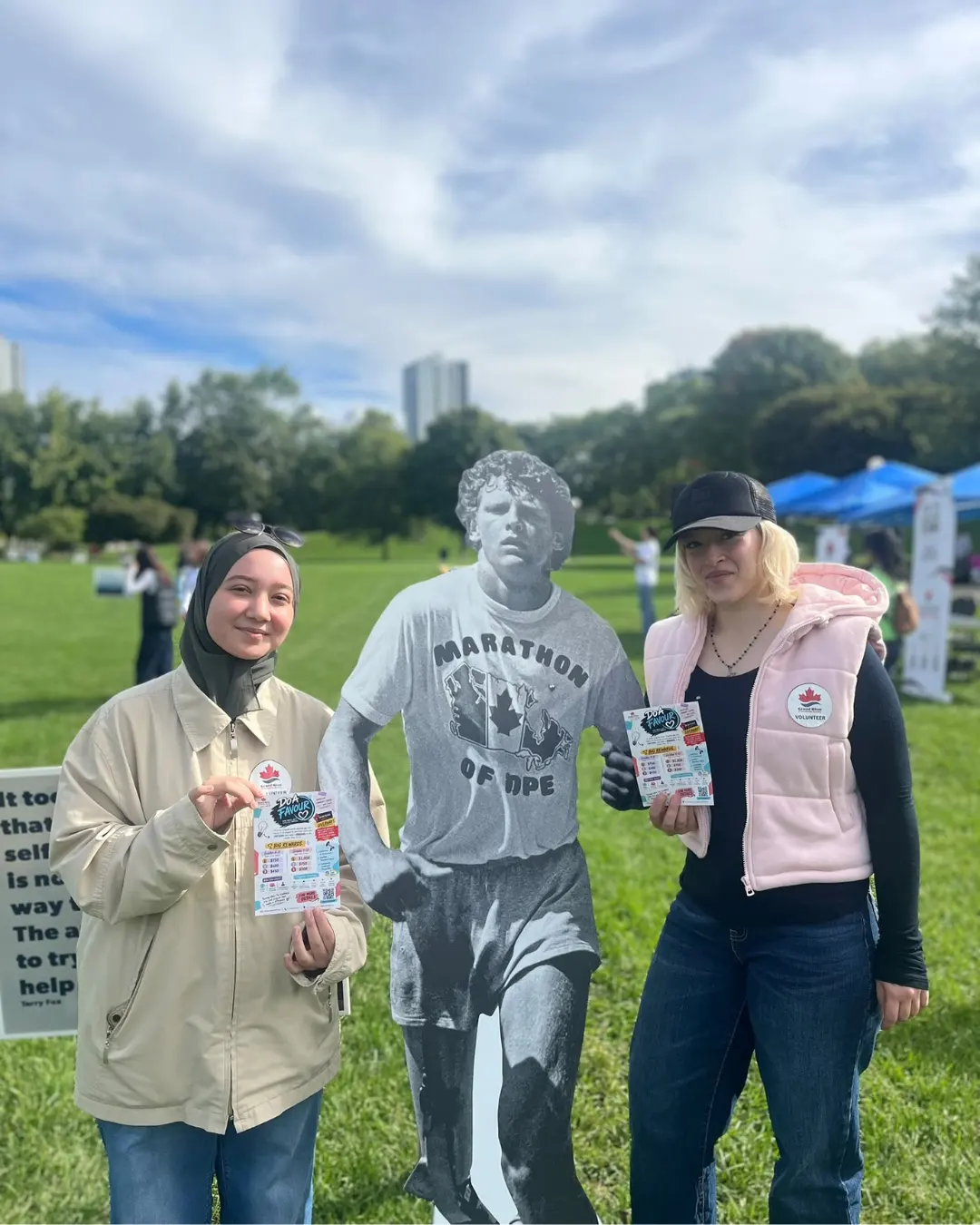 GRFS volunteers holding Do A Favour flyers beside a Terry Fox display