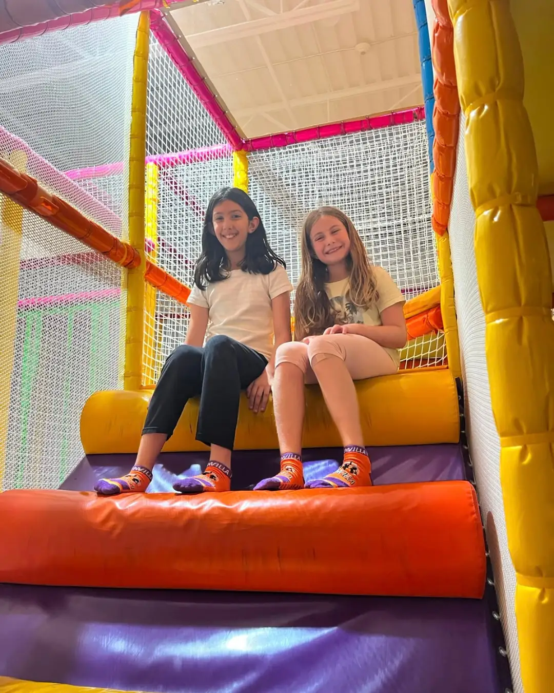 Two children sitting together on colourful indoor play equipment at GRFS Summer School 2026