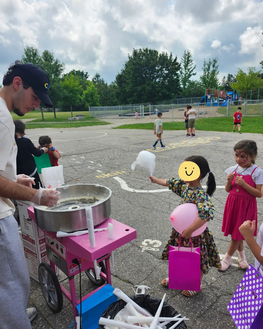A volunteer preparing cotton candy for children outdoors at GRFS Summer School 2026
