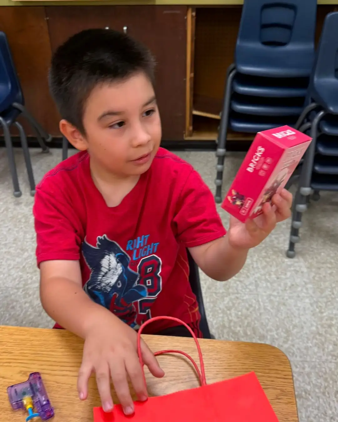 A child opening a gift bag in the classroom at GRFS Summer School 2026