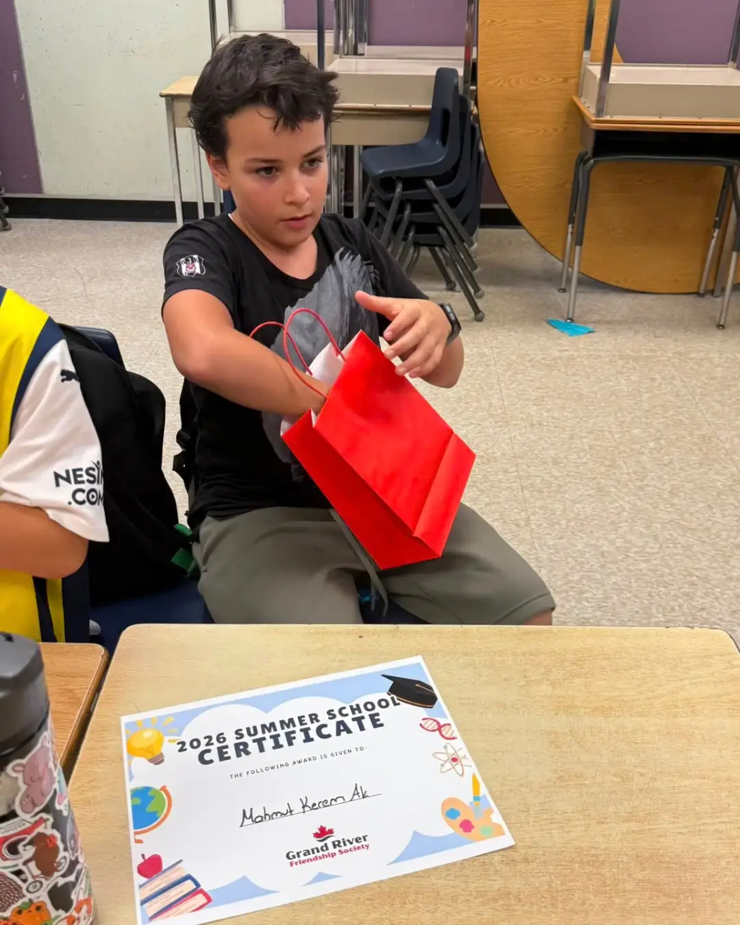 A child with a gift bag and Summer School completion certificate at GRFS Summer School 2026