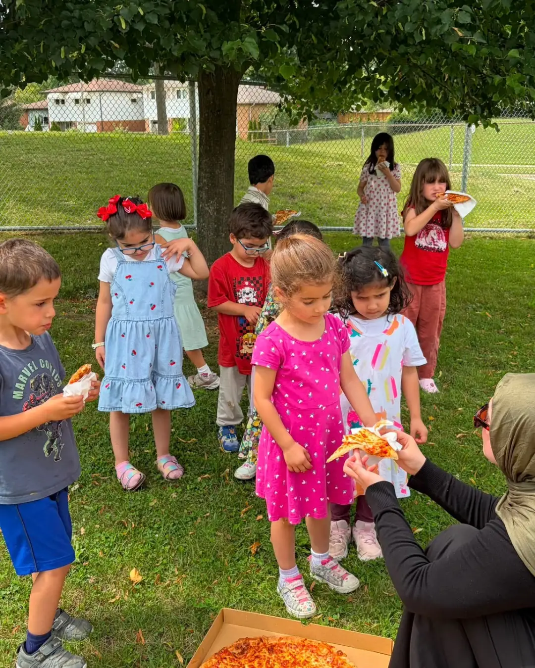 Children sharing pizza during an outdoor lunch at GRFS Summer School 2026