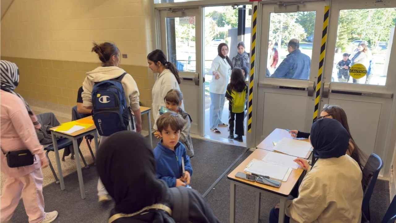 Families and children checking in with volunteers for GRFS Football for Learning Fall 2026.